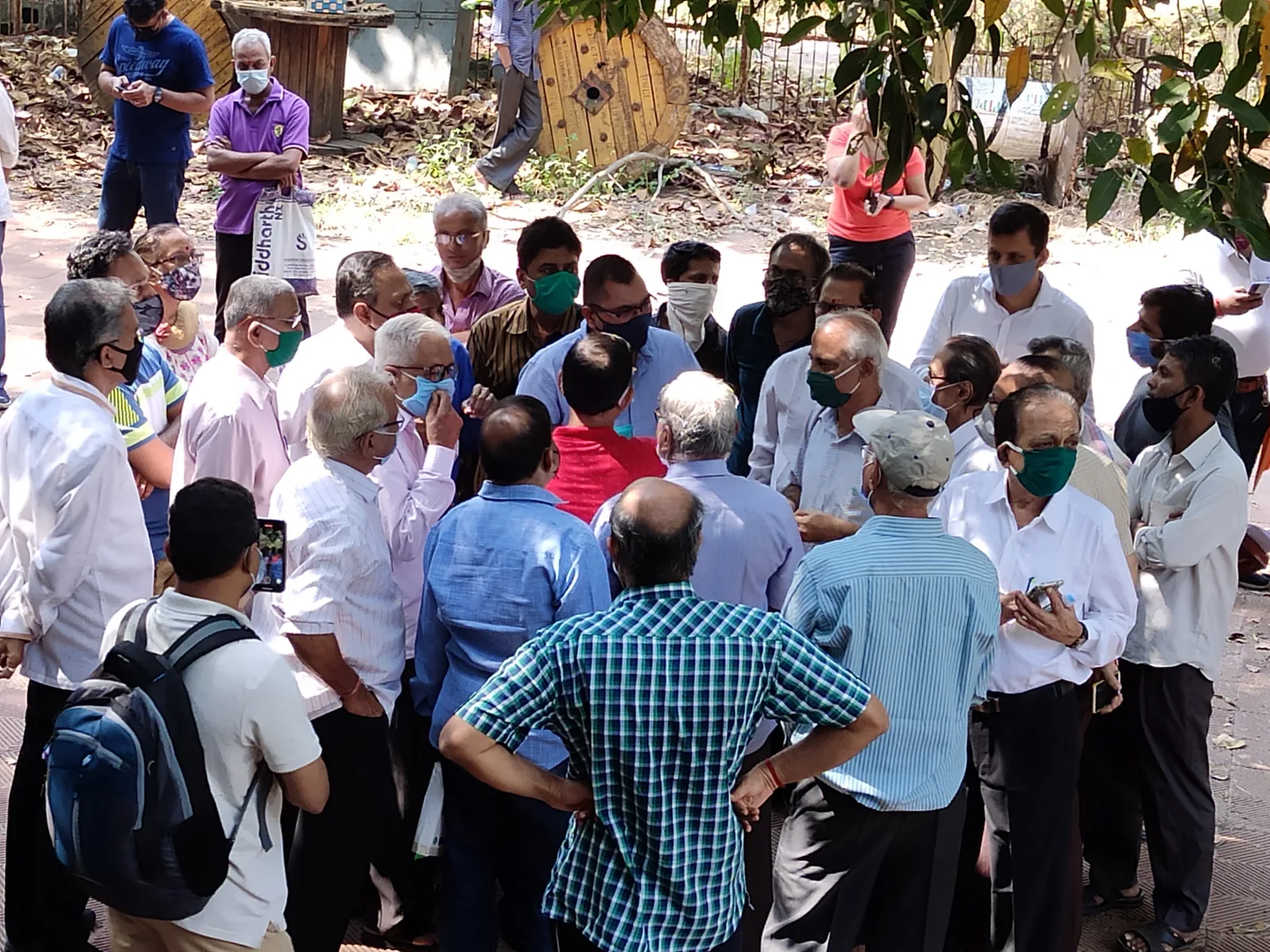 Residents gather outdoors in a circle for a society discussion.